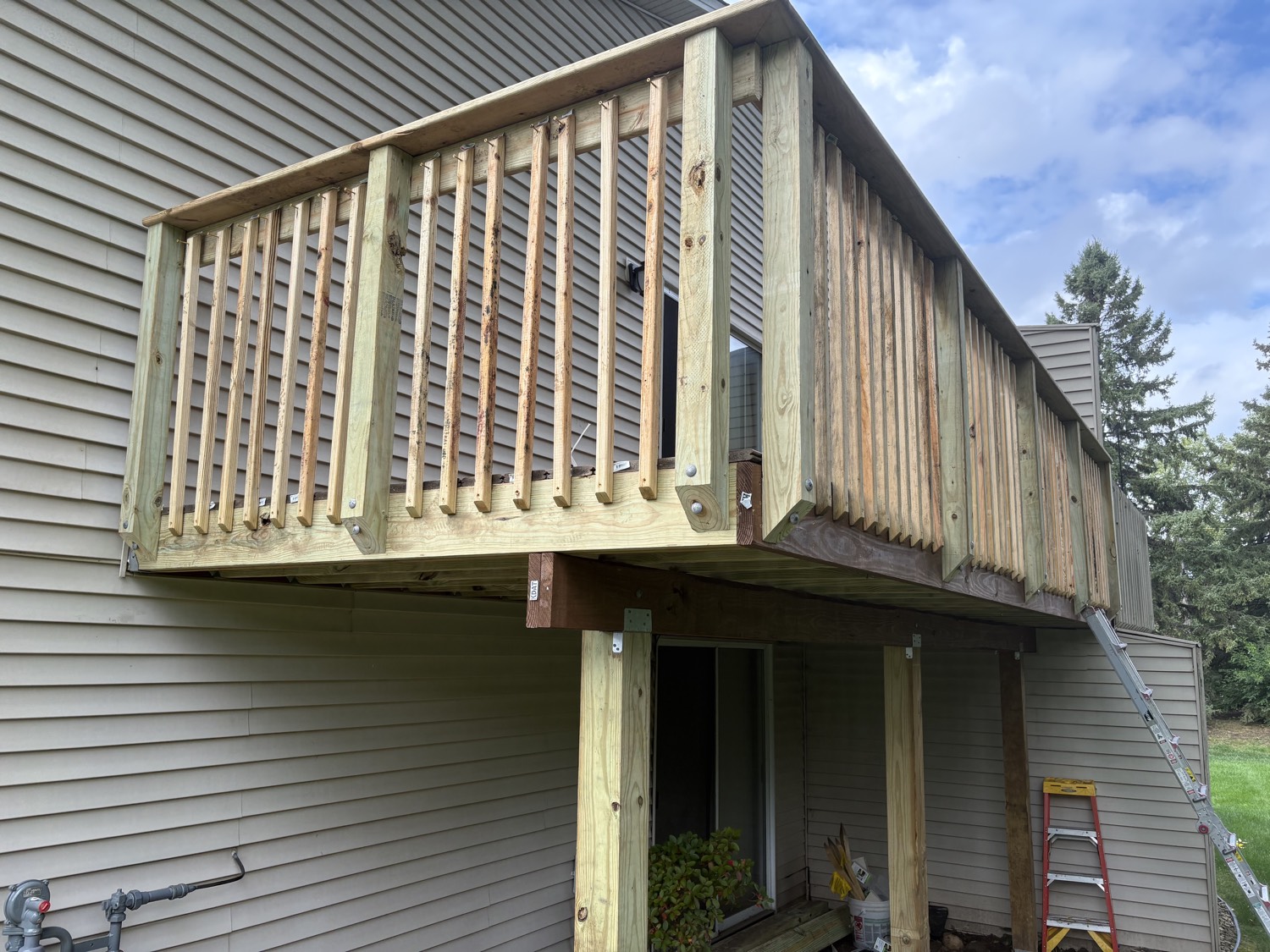 Wooden deck under construction, with railing posts and beams attached to the house